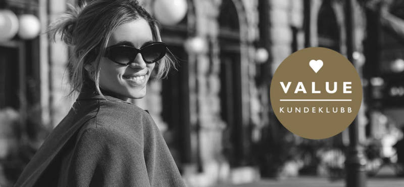 sorthvitt-bilde av en smilende dame i byen + value logo